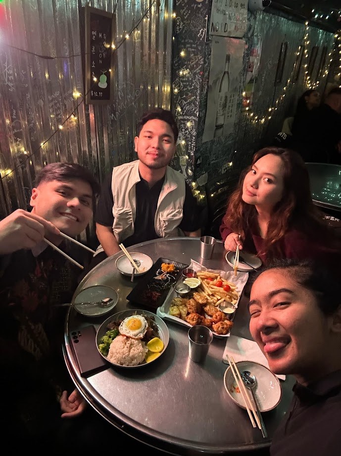 Four of us around a metal table under fairy lights in a graffiti covered bar