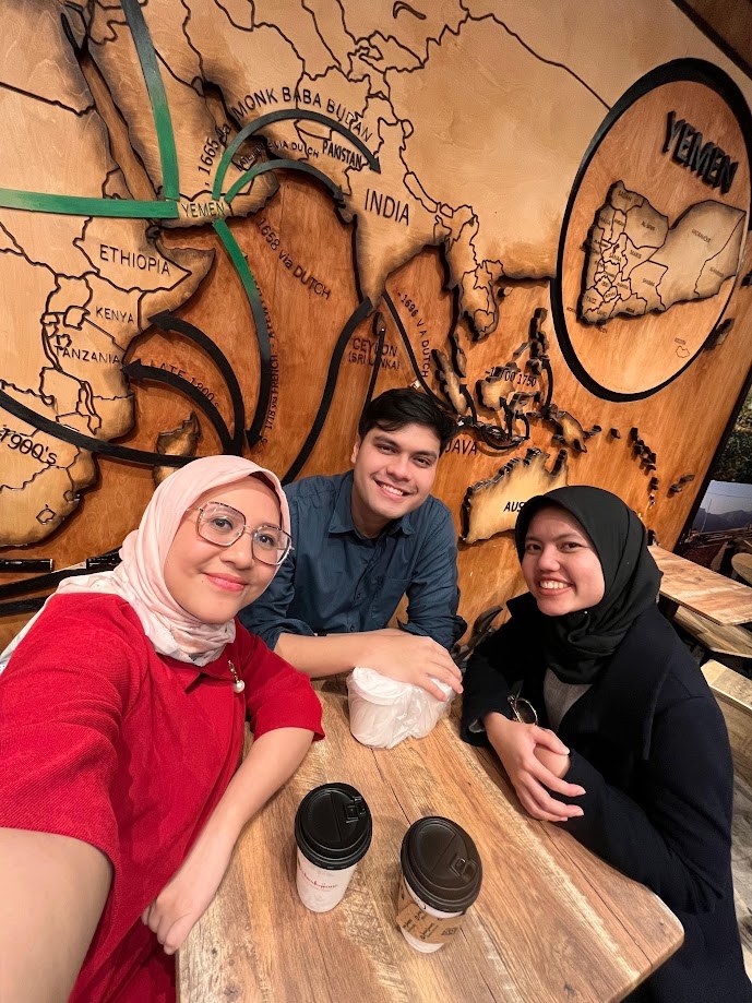 Coffee with friends under a carved wooden map of the coffee trade routes