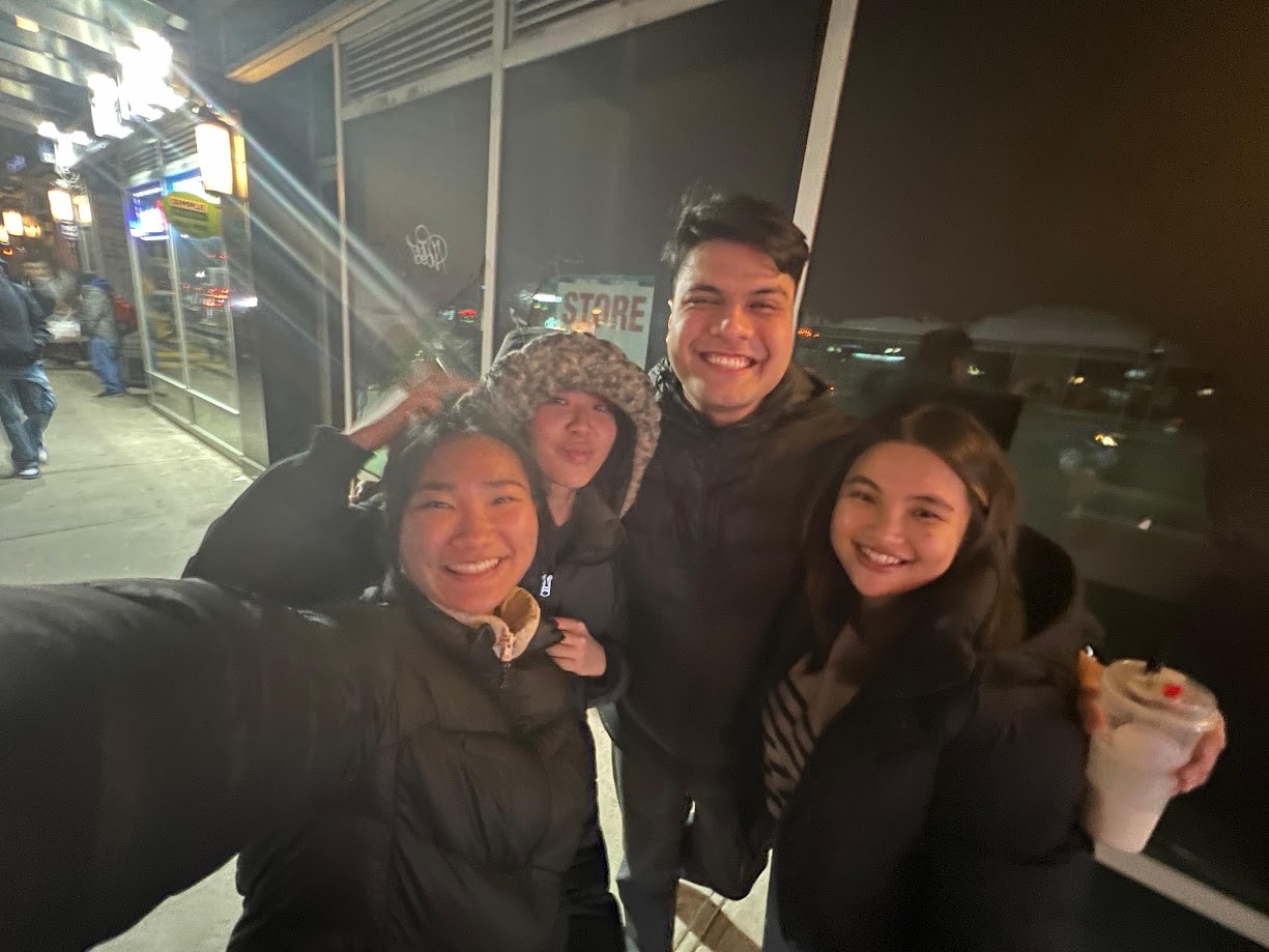 Four of us bundled up outside a store at night, drinks in hand