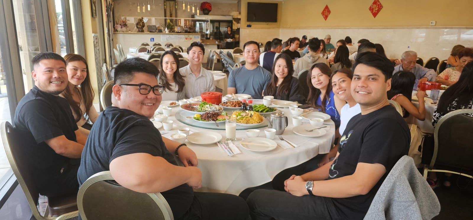 A full round table of dim sum with everyone turned to the camera