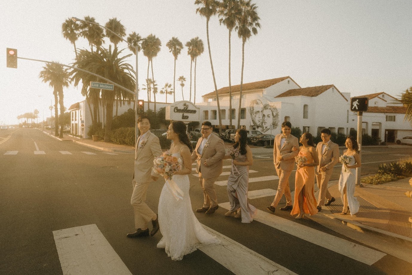 The wedding party crossing the street at sunset under the palms