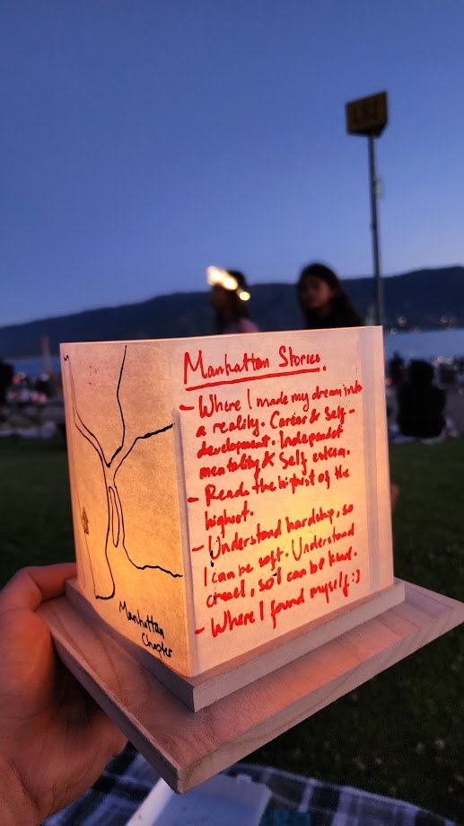 A paper lantern at dusk, Manhattan Stories written on it in red with the Manhattan Chapter noted on the base