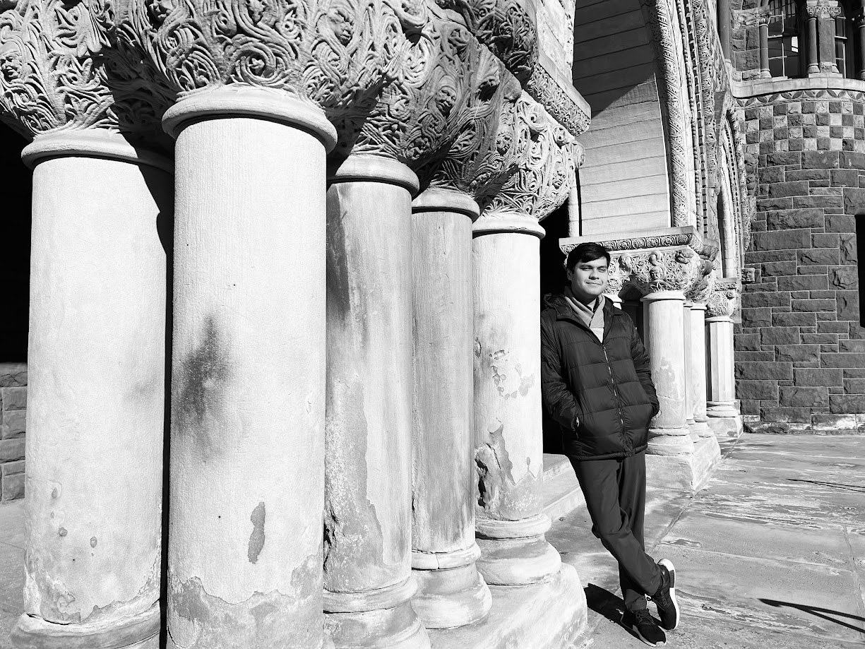 Black and white, leaning against the stone columns of a Romanesque porch