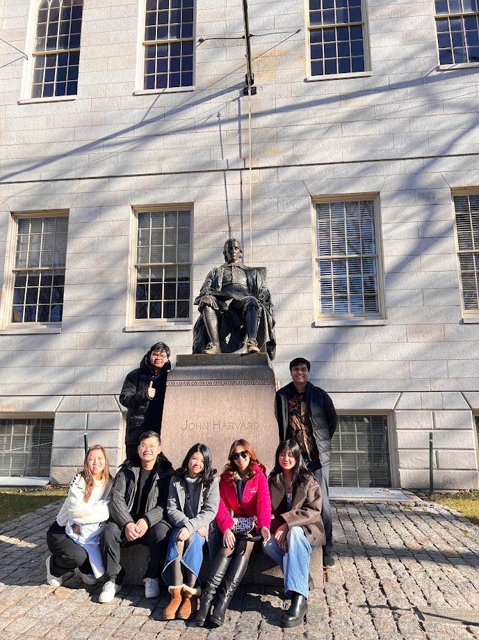 The group gathered around the John Harvard statue in the winter sun