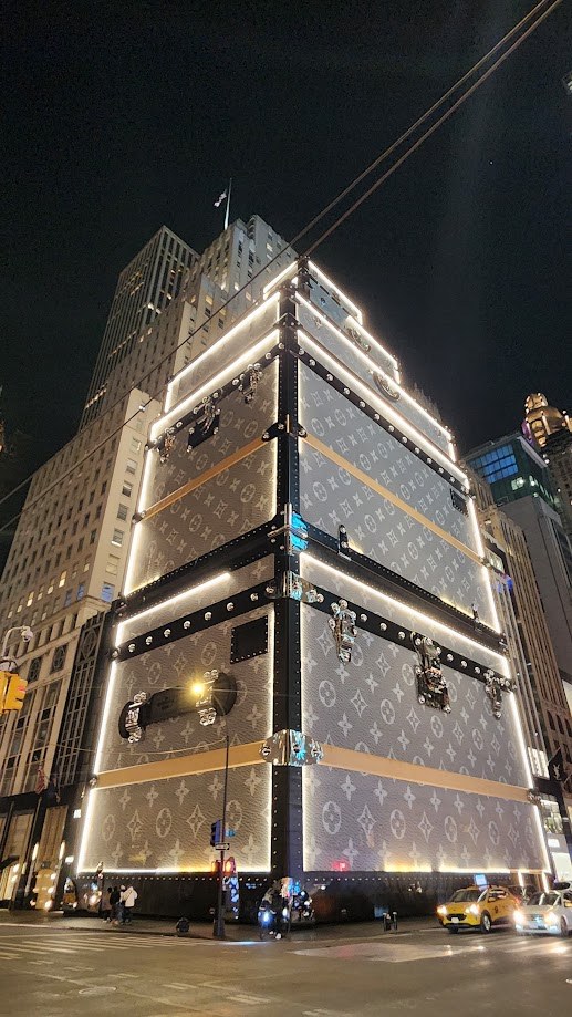 The Louis Vuitton building on Fifth Avenue wrapped as a giant lit trunk at night