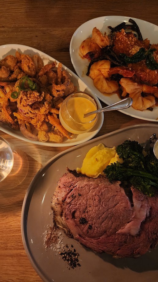 Prime rib, calamari and greens spread across the table