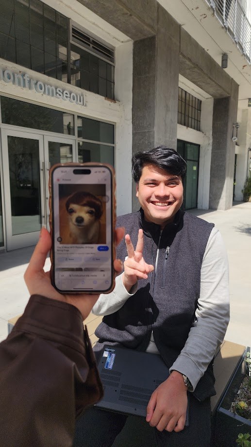 A friend holding up a phone with a dog on the screen, both of us grinning