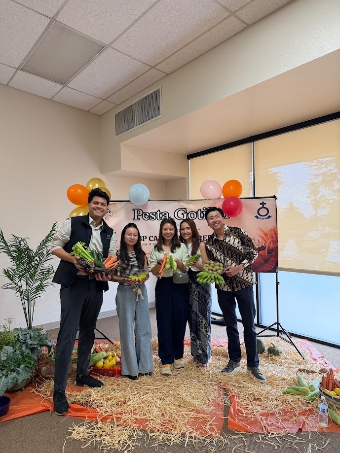 On stage at the HKBP California Pesta Gotilon holding an armful of vegetables
