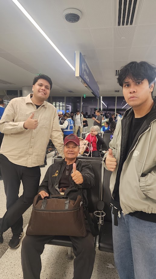 The three of us giving a thumbs up at the airport gate, my dad in a wheelchair between us