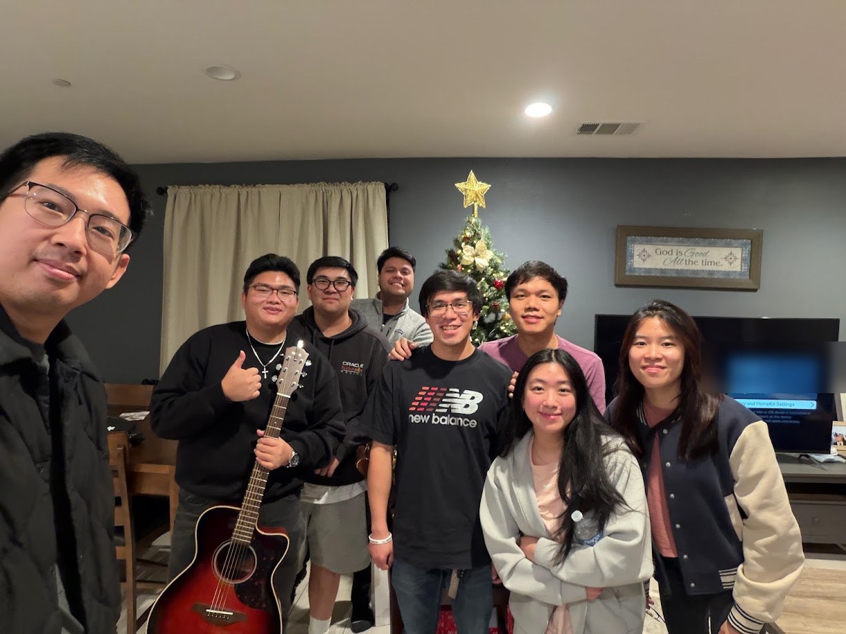 Group photo by the Christmas tree, one of us holding a guitar